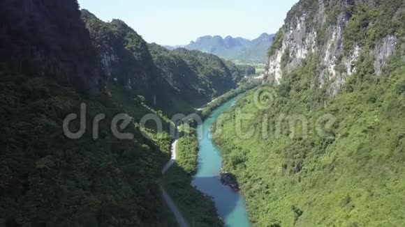 鸟瞰绿色峡谷中平静的河流和空旷的公路视频的预览图