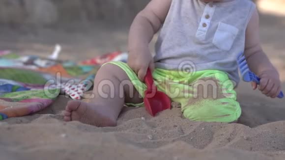 可爱的小宝宝用桨耙和沙子在海滩上玩耍视频的预览图