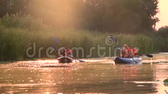 两条皮划艇和人们一起划进夕阳慢动作视频的预览图
