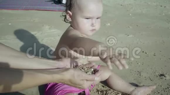 母亲和女儿穿着粉红色泳衣在海边的沙滩上玩耍幸福家庭的概念4k视频的预览图