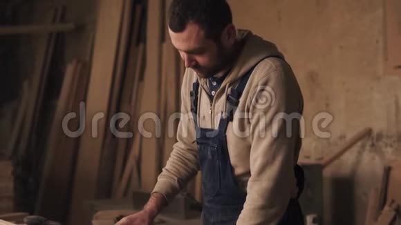 一个穿工作服的木匠的录像一个人在木工店里磨木头慢动作视频的预览图