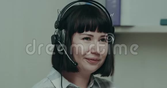 年轻漂亮的女接线员在呼叫中心用耳机与客户交谈视频的预览图