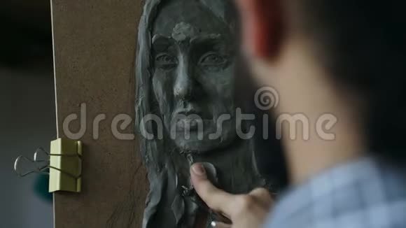 雕塑家的特写镜头在艺术工作室的画布上创作人的面部雕塑视频的预览图