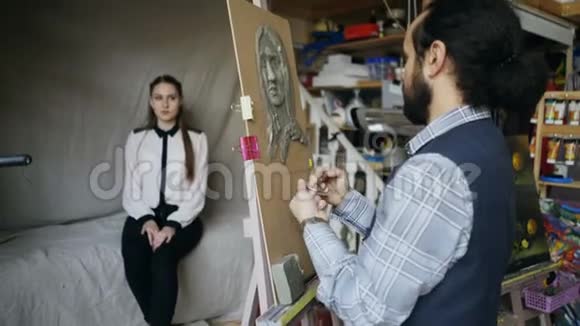熟练的雕塑家在画布上用橡皮泥创作女性在艺术工作室摆模特的脸视频的预览图