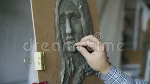 雕塑家的特写镜头在画室里年轻女子向他摆姿势在画布上人的脸视频的预览图