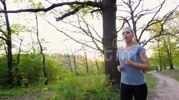 穿T恤的美女在春天的森林里奔跑视频的预览图
