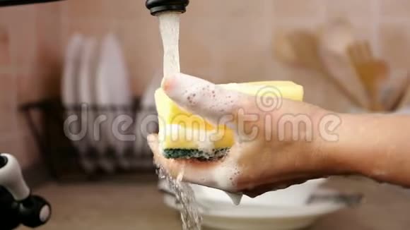 女人在洗碗的时候在厨房的水龙头上洗手视频的预览图