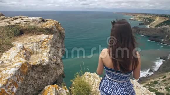 坐在岩石上看海景的女人视频的预览图