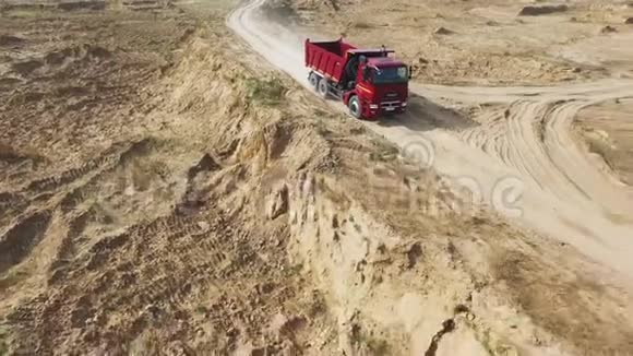 在狭窄的砂石跑道上移动的大型和空的红色自卸卡车场景从上面看视频的预览图