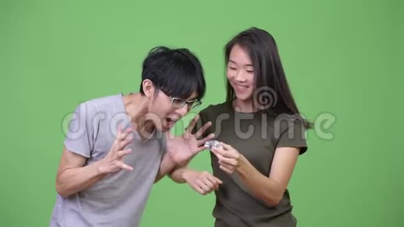 年轻的亚洲夫妇一起玩坐立不安的旋转游戏视频的预览图