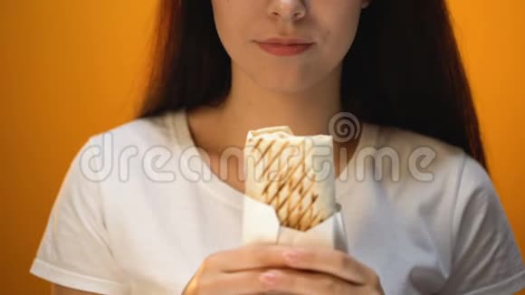 女孩吃三明治享受味道便宜美味但不健康的食物特写视频的预览图