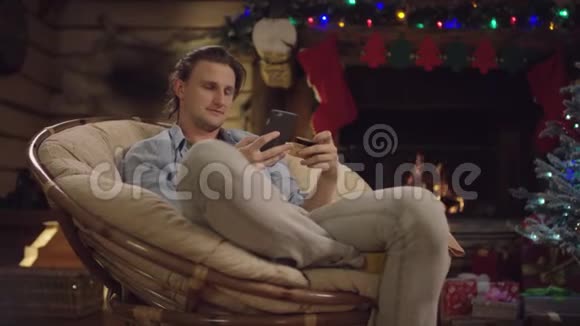 在圣诞夜使用智能手机和信用卡在线购物的长头发帅哥视频的预览图