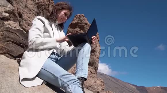 坐在山上的女孩用笔记本电脑打字视频的预览图