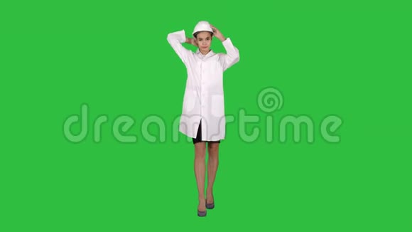 女工程师穿着白色长袍和白色安全帽走在绿色屏幕上Chroma键视频的预览图