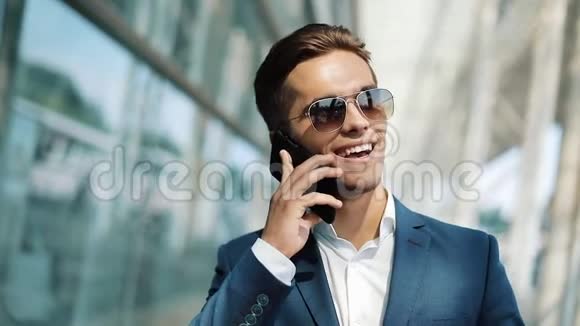 漂亮的商人站在办公室中心附近用智能手机说话商务风格旅行者交流视频的预览图