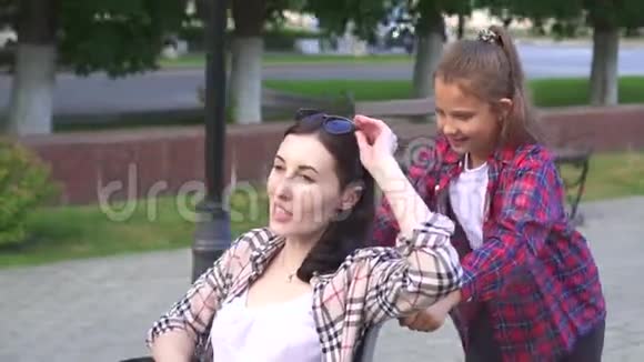 小女孩帮助一个残疾人的母亲在轮椅上行走视频的预览图
