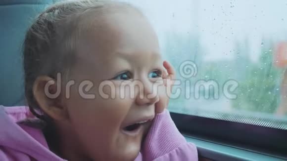 快乐惊讶的孩子在乘公共汽车旅行时看着潮湿的窗户视频的预览图