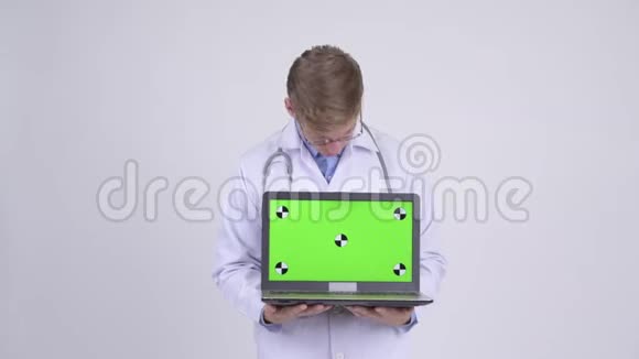 快乐的年轻帅哥医生一边思考一边看笔记本电脑视频的预览图
