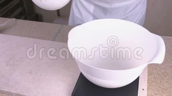 厨师把液体黑巧克力倒在白色的碗里站在鳞片上特写镜头视频的预览图