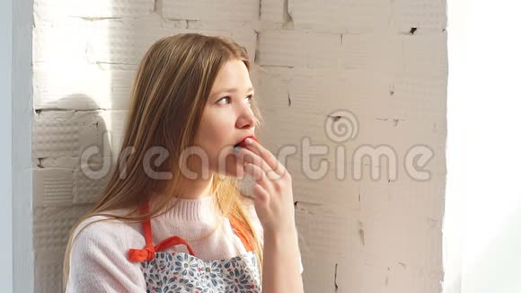 年轻女子坐在窗边享受她的纸杯蛋糕视频的预览图