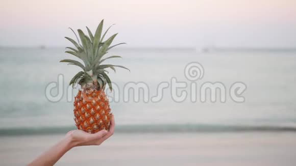 靠近女人手拿着海滩上的菠萝鸡尾酒视频的预览图