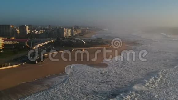 雾天在葡萄牙波沃阿德瓦尔齐姆市海滩和城市上空拍摄日落视频的预览图
