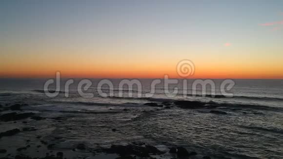在葡萄牙美丽的蓝橙色渐变的天空下在黑暗的海洋上拍摄日落视频的预览图