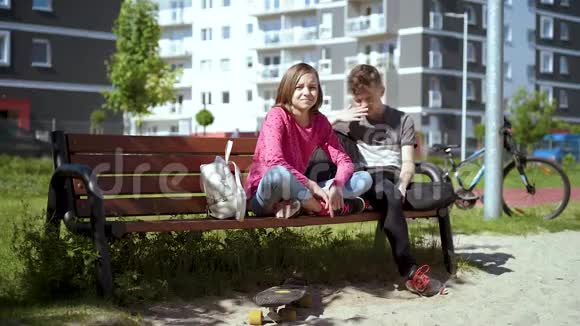 坐在长凳上的男孩和女孩视频的预览图