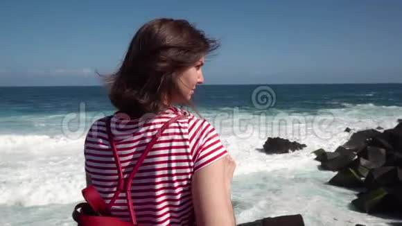 女游客带着望远镜沿着海洋行走视频的预览图