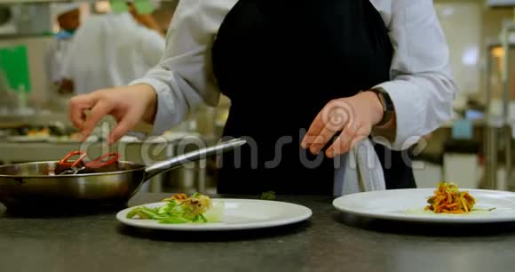 女厨师在厨房的餐盘上安排食物视频的预览图