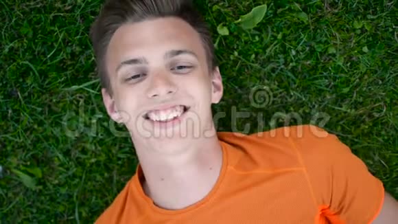 一个十几岁的男孩躺在草地上休息漫不经心地笑着视频的预览图