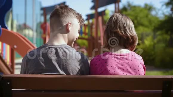 坐在长凳上的男孩和女孩视频的预览图