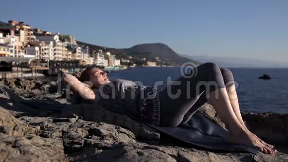 小女孩在海边的岩石上做运动视频的预览图