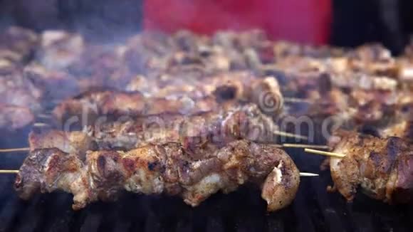 男人在烧烤烧烤架上为他的朋友在夏季户外聚会上煮肉用热炭煮猪肉特写视频的预览图