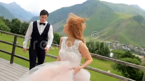 美丽的新婚夫妇穿着豪华的衣服在群山的背景下度过了许多乐趣视频的预览图
