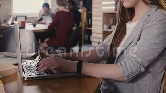 集中精力的欧洲年轻女孩在笔记本电脑上打字在时髦的办公空间努力工作在4K背景下团队合作视频的预览图