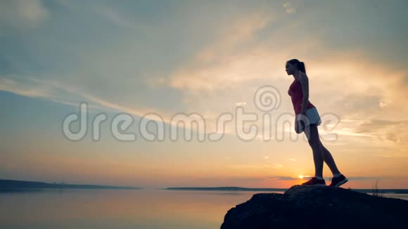 一个女孩摆姿势同时在日落背景下训练4K视频的预览图