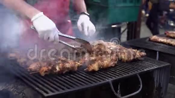 男人在烧烤烧烤架上为他的朋友在夏季户外聚会上煮肉用热炭煮猪肉特写视频的预览图