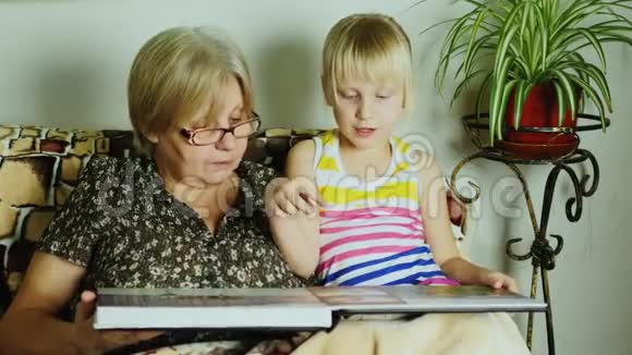孙女和祖母正在翻阅这张专辑和家庭照片视频的预览图