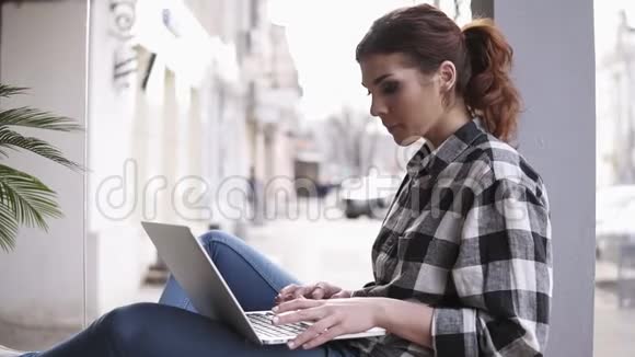 集中长发美丽的女孩在笔记本电脑在轻型工作空间侧视背景模糊视频的预览图