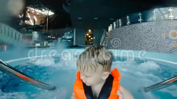 穿着救生衣穿着按摩浴缸的男孩的肖像慢动作4k视频的预览图