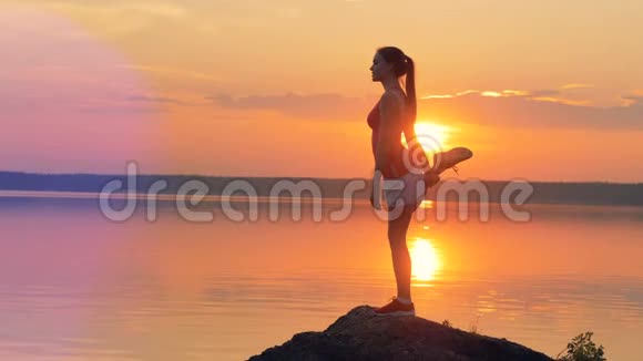 女性慢跑者在湖边做瑜伽姿势视频的预览图