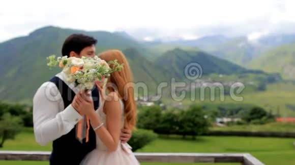美丽的新娘和新郎在雄伟的群山背景上捧着一束鲜花视频的预览图
