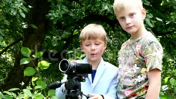 年轻的男孩用摄像机拍摄关于自然的绿色公园背景视频的预览图