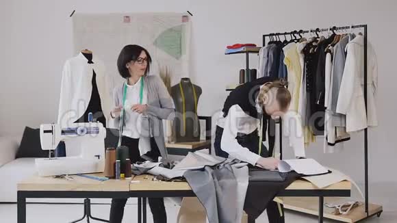 管闲事的舞蹈和有趣的工作两名服装设计师在一个创意工作室进行裁剪时装设计师视频的预览图