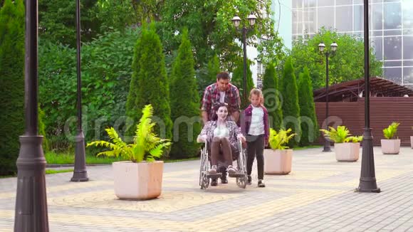 十几岁的女孩和一个男人在公园里抱着一个坐轮椅的残疾妇女视频的预览图