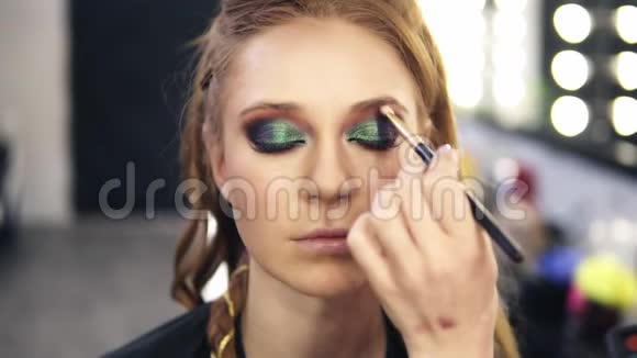 化妆造型师完成了绿色光滑的眼睛弥补了白皙的头发模型她慢慢睁开眼睛前景慢慢视频的预览图