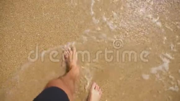 男人双腿在海沙和海浪上在海洋海滩上放松暑假视频的预览图