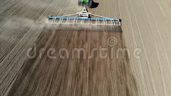 农业耕作拖拉机在大轮犁上的空中视野在肥沃的农田上耙土饲养视频的预览图