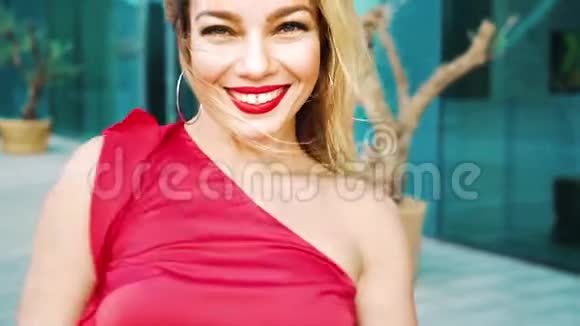一幅美丽的金发女人的肖像她的红口红穿着红裙子在外面跳舞视频的预览图